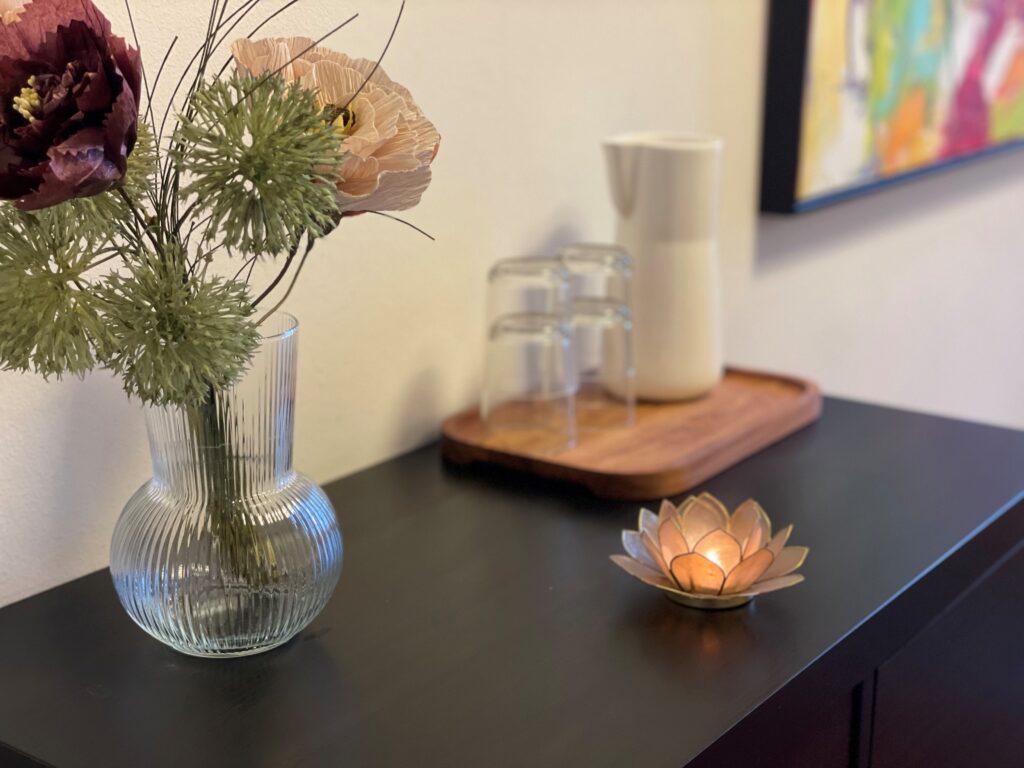 Vase med blomster og lotusblomst fyrfadsstage og træbakke med glas og kande på sort skab giver ro og balance i terapirum hos psykoterapeut i Århus C psykoterapeut Christina Stigbjerg